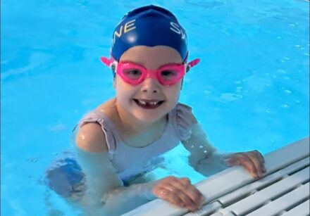 6-year-old girl in a swimming pool smiling at the camera