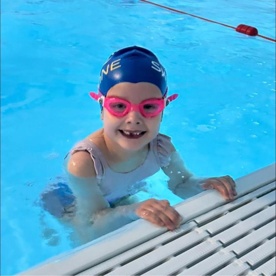 6-year-old girl in a swimming pool smiling at the camera