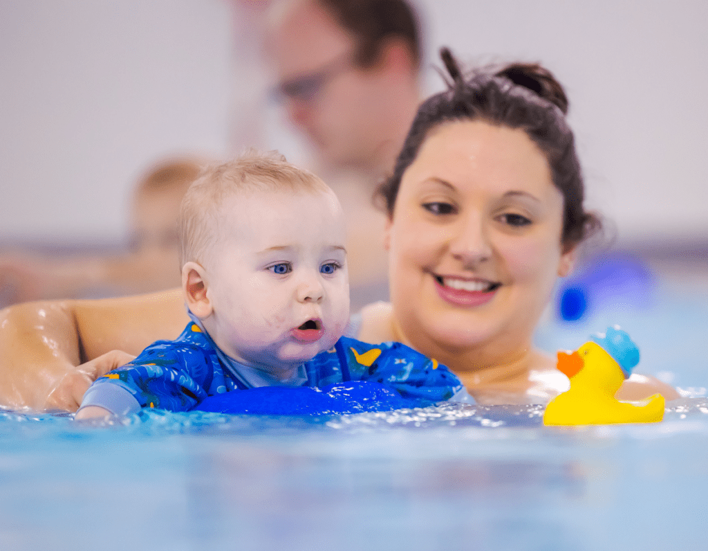 A mum and baby move through the swimming pool trying to catch a rubber duck