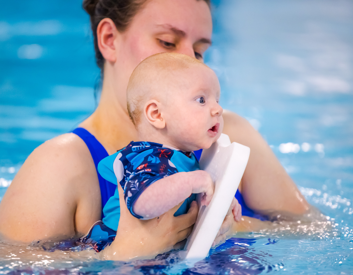 A young baby in the swimming pool with mum