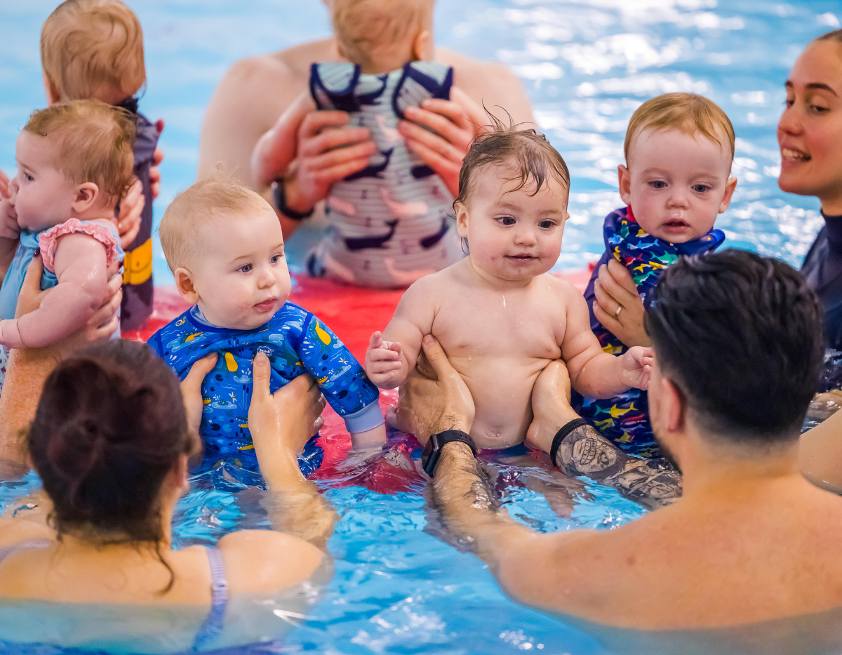 A group of babies and their parents enjoy a swimming class together