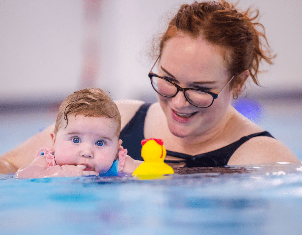 A mum supports baby in the swimming pool